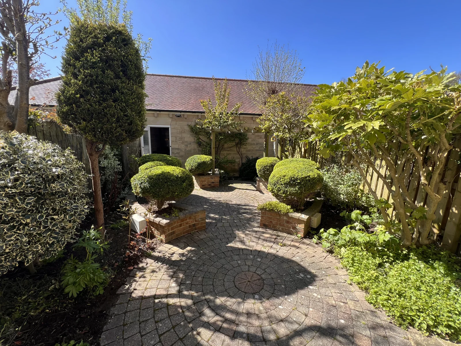 Courtyard garden with topiary, cobbled paving and stone cottage, North Leeds